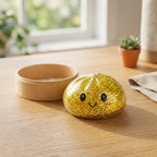 Squishy Dumpling Doré à Paillettes — posé sur un bureau