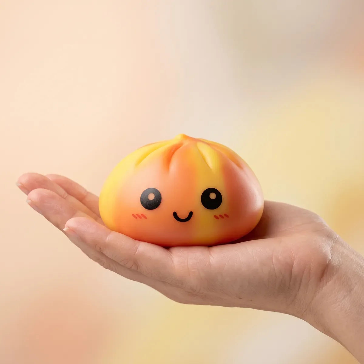 Squishy Dumpling Tie & Dye Orange — tenu dans la main, échelle réelle
